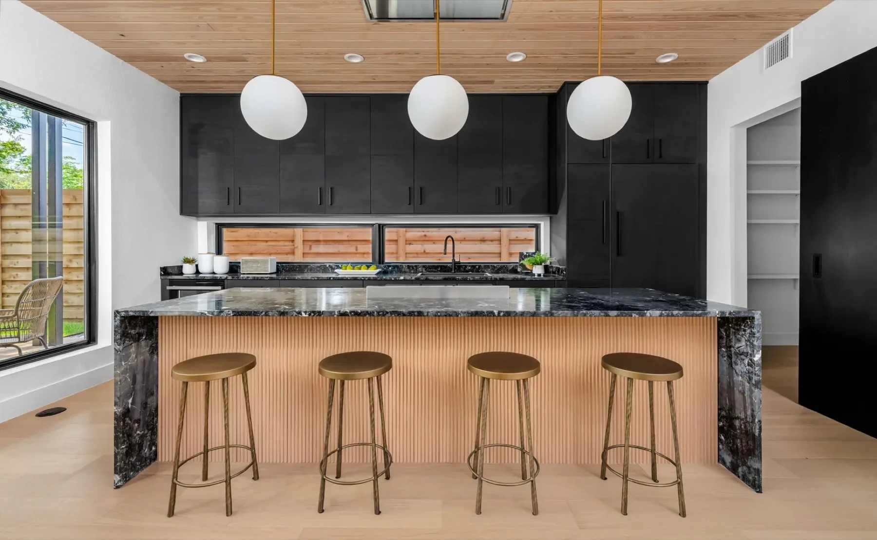 Southern Oaks Residence kitchen with matte-black cabinetry and a fluted wood island base